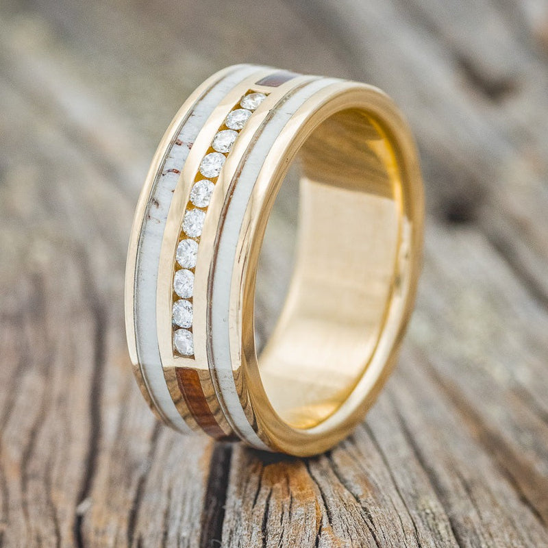 Shown here is "Rio", a custom, handcrafted men's wedding ring featuring 3 channels with elk antler and ironwood inlays, upright facing left. The middle section also has a section of 10 diamonds on a 14K gold band. Additional inlay options are available upon request.