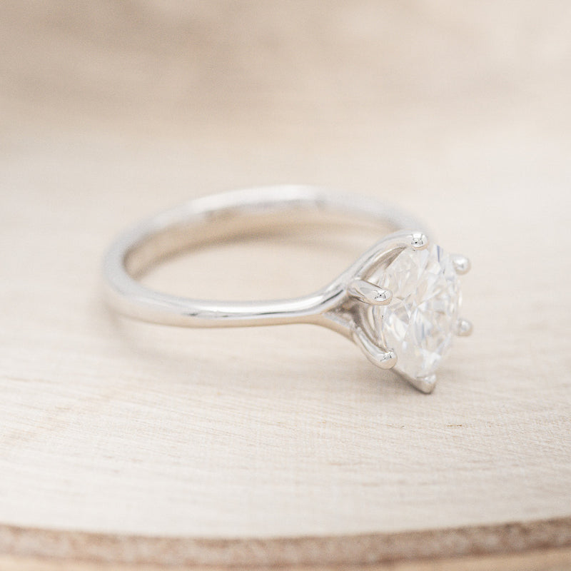 Shown here is "Tulip", a solitaire-style oval moissanite women's engagement ring with a split shank band, facing right. Many other center stone options are available upon request.