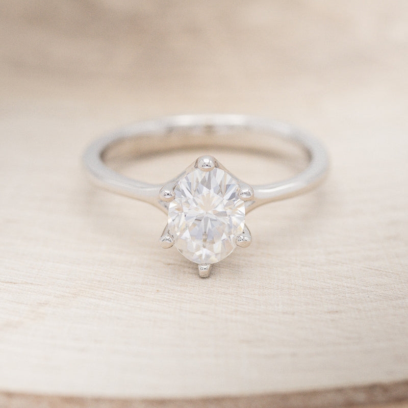 Shown here is "Tulip", a solitaire-style oval moissanite women's engagement ring with a split shank band, front facing. Many other center stone options are available upon request.
