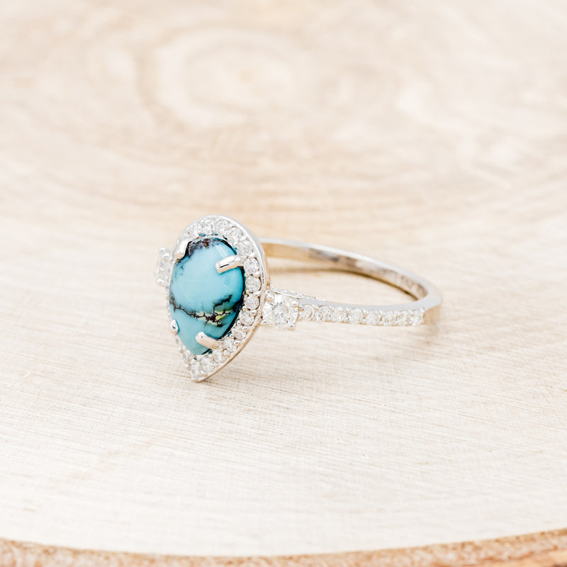 Shown here is "KB", a turquoise women's engagement ring with a diamond halo and diamond accents, facing left. Many other center stone options are available upon request.