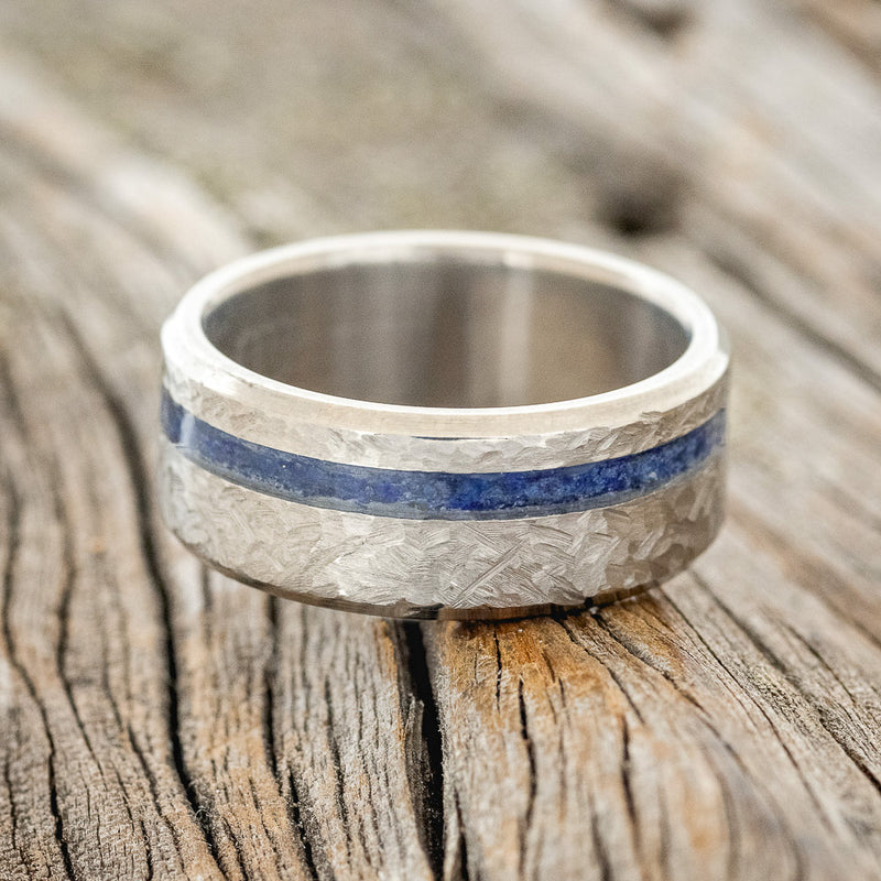 Shown here is "Vertigo", a handcrafted men's wedding ring featuring a lapis lazuli inlay with a crosshatched finish, laying flat.