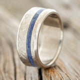 Shown here is "Vertigo", a custom, handcrafted men's wedding ring featuring a lapis lazuli inlay with a crosshatched finish, upright facing left. Additional inlay options are available upon request.