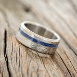 Shown here is "Vertigo", a handcrafted men's wedding ring featuring a lapis lazuli inlay with a crosshatched finish, tilted left.