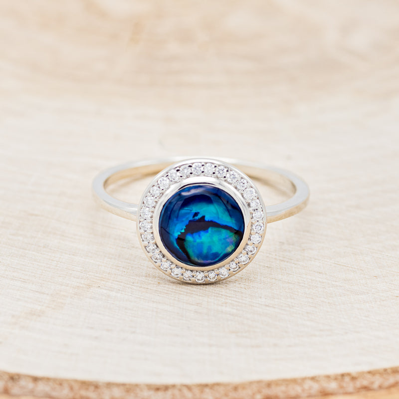 Shown here is "Terra", a round paua shell women's engagement ring with a diamond halo, front facing. Many other center stone options are available upon request.