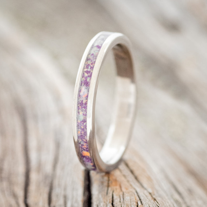 Shown here is "Eterna", a custom, handcrafted women's stacking band featuring a sugilite inlay mixed with fire & ice opal, shown here on a titanium band, upright facing left. Additional inlay options are available upon request.