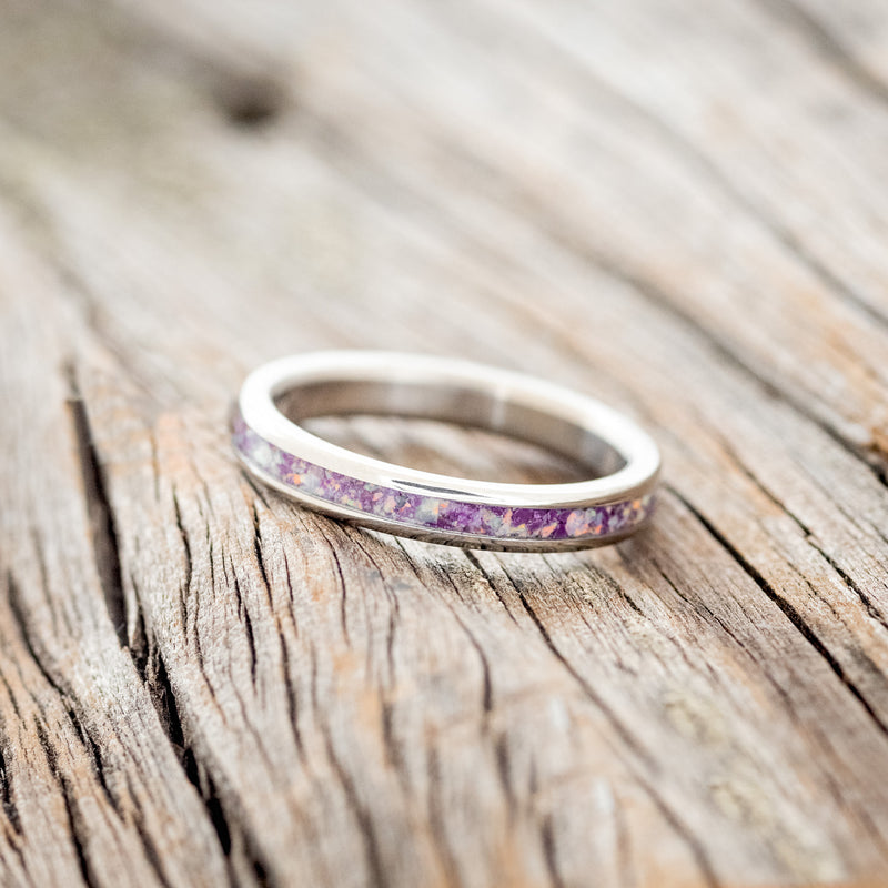 Shown here is "Eterna", a custom, handcrafted women's stacking band featuring a sugilite inlay mixed with fire & ice opal, shown here on a titanium band, tilted left. Additional inlay options are available upon request.