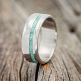Shown here is "Vertigo", a handcrafted men's wedding ring featuring an inlay of a malachite and opal mixture, upright facing left. 