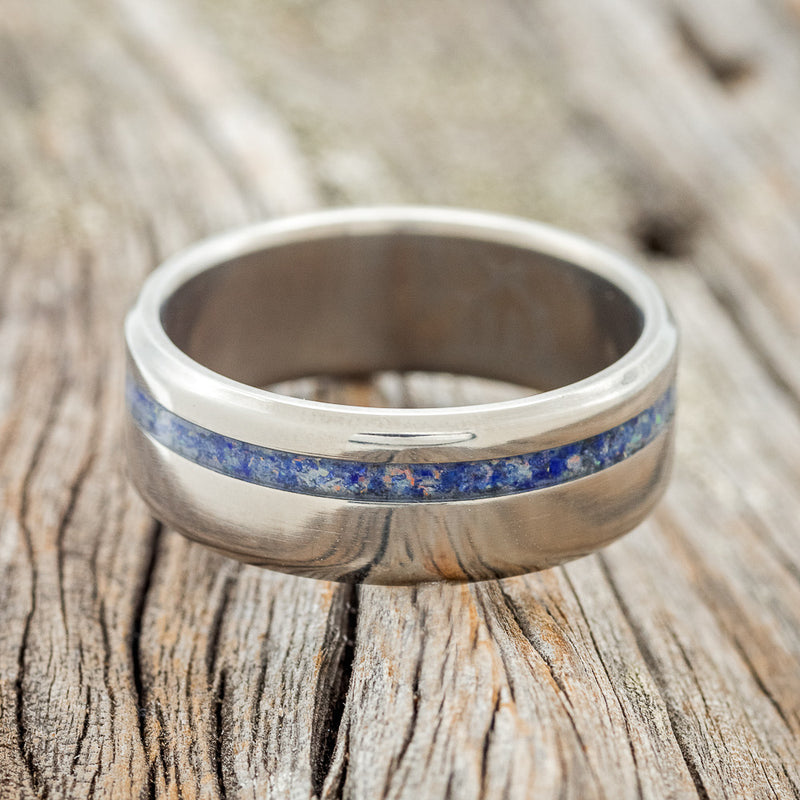 Shown here is "Vertigo", a custom, handcrafted men's wedding ring featuring a beautiful mixture of lapis lazuli & fire and ice opal inlay, laying flat. Additional inlay options are available upon request.
