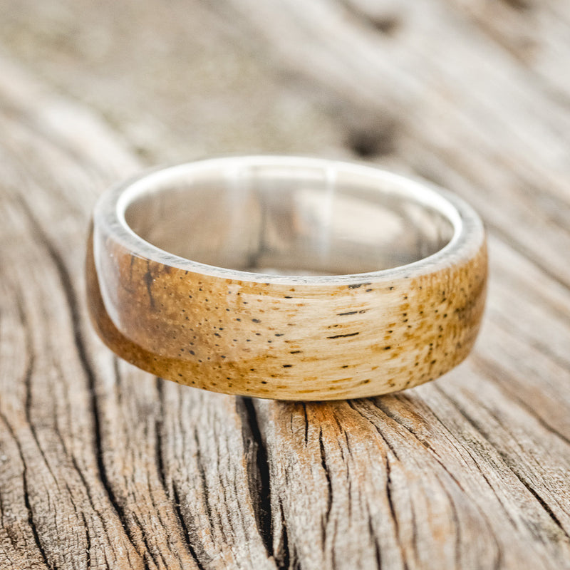 Shown here is "Haven", a custom, handcrafted men's wedding ring featuring a spalted maple wood overlay, laying flat. Additional overlay options are available upon request.
