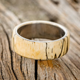 Shown here is "Haven", a custom, handcrafted men's wedding ring featuring a spalted maple wood overlay, laying flat. Additional overlay options are available upon request.