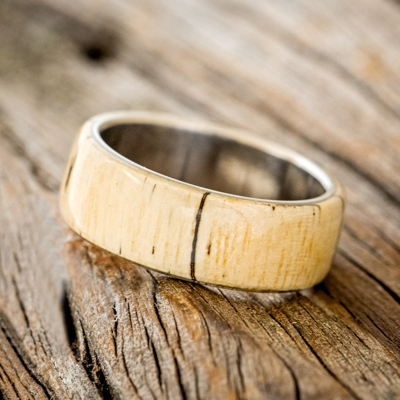 Shown here is "Haven", a custom, handcrafted men's wedding ring featuring a spalted maple wood overlay, tilted left. Additional overlay options are available upon request.