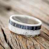 Shown here is "Dyad", a custom, handcrafted men's wedding ring featuring 2 channels with grey birch wood and antler inlays, tilted left.