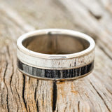 Shown here is "Dyad", a custom, handcrafted men's wedding ring featuring 2 channels with grey birch wood and antler inlays, shown here on a titanium band, laying flat. Additional inlay options are available upon request.