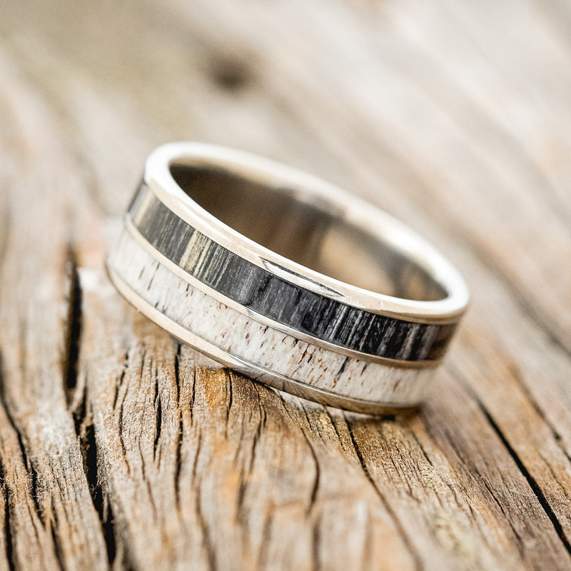 Shown here is "Dyad", a custom, handcrafted men's wedding ring featuring 2 channels with grey birch wood and antler inlays, shown here on a titanium band, tilted left. Additional inlay options are available upon request.