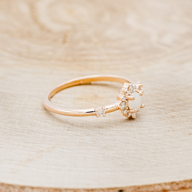 Shown here is "Starla", a round cut opal women's engagement ring with a starburst diamond halo, facing right. Many other center stone options are available upon request.