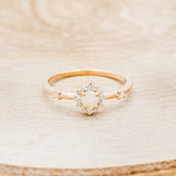 Shown here is "Starla", a round cut opal women's engagement ring with a starburst diamond halo, front facing. Many other center stone options are available upon request.