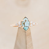 Shown here is "Raya", a turquoise women's engagement ring with diamond accents, on stand front facing. Many other center stone options are available upon request.