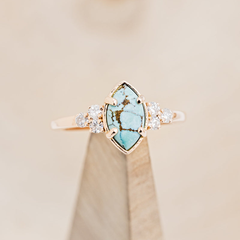 Shown here is "Raya", a turquoise women's engagement ring with diamond accents, on stand front facing. Many other center stone options are available upon request.