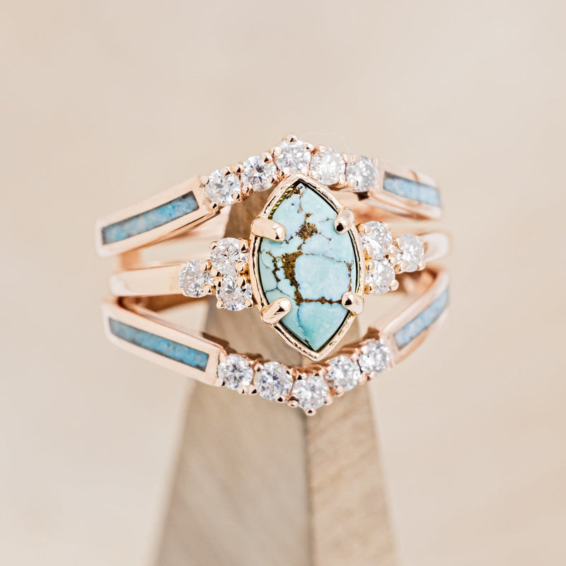 Shown here is "Raya", a turquoise women's engagement ring with diamond accents and a ring guard, on stand front facing. Many other center stone options are available upon request. 