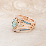 Shown here is "Raya", a turquoise women's engagement ring with diamond accents and a ring guard, facing left. Many other center stone options are available upon request.