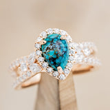 Shown here is "Loretta", a split shank-style turquoise women's engagement ring with a diamond halo and leaf-shape diamond accents, on stand front facing. Many other center stone options are available upon request.  