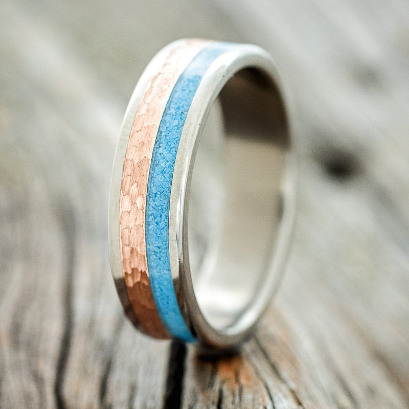 Shown here is a custom, handcrafted men's wedding ring featuring turquoise and hammered 14K rose gold inlay, upright facing left. Additional inlay options are available upon request.