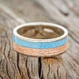 Shown here is a custom, handcrafted men's wedding ring featuring turquoise and hammered 14K rose gold inlay, laying flat. Additional inlay options are available upon request.