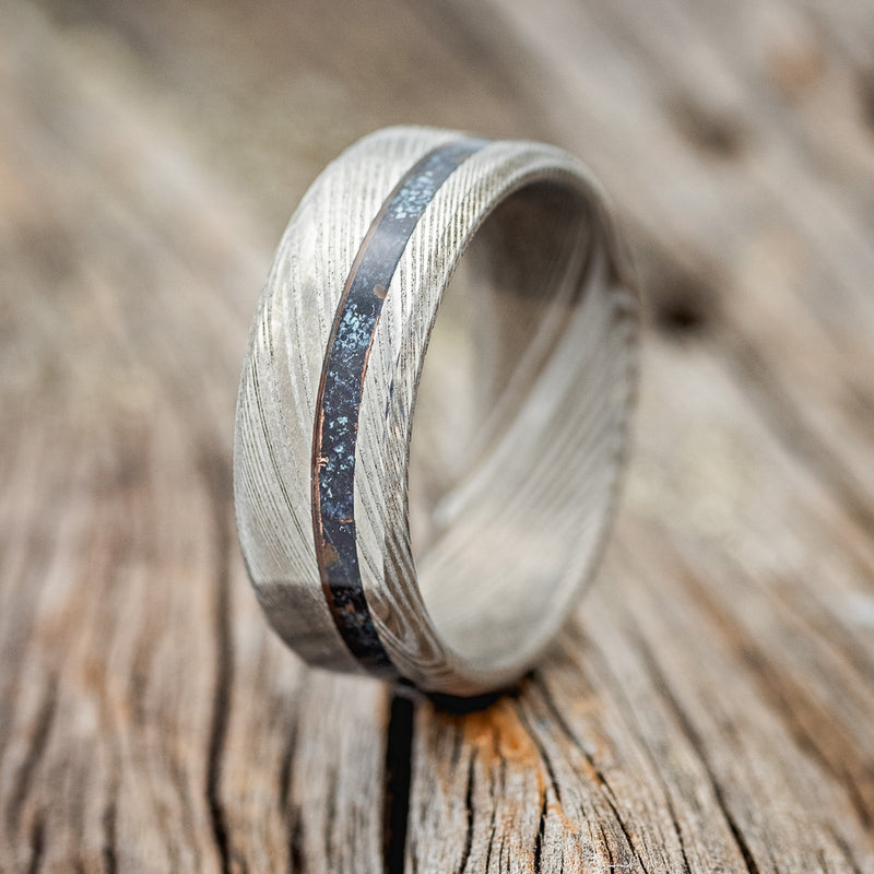 Shown here is "Vertigo", a custom, handcrafted men's wedding ring featuring a patina copper inlay, upright facing left. Additional inlay options are available upon request.
