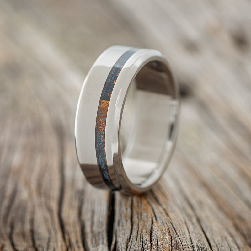 Shown here is "Vertigo", a handcrafted men's wedding ring shown featuring a patina copper inlay, upright facing left. 