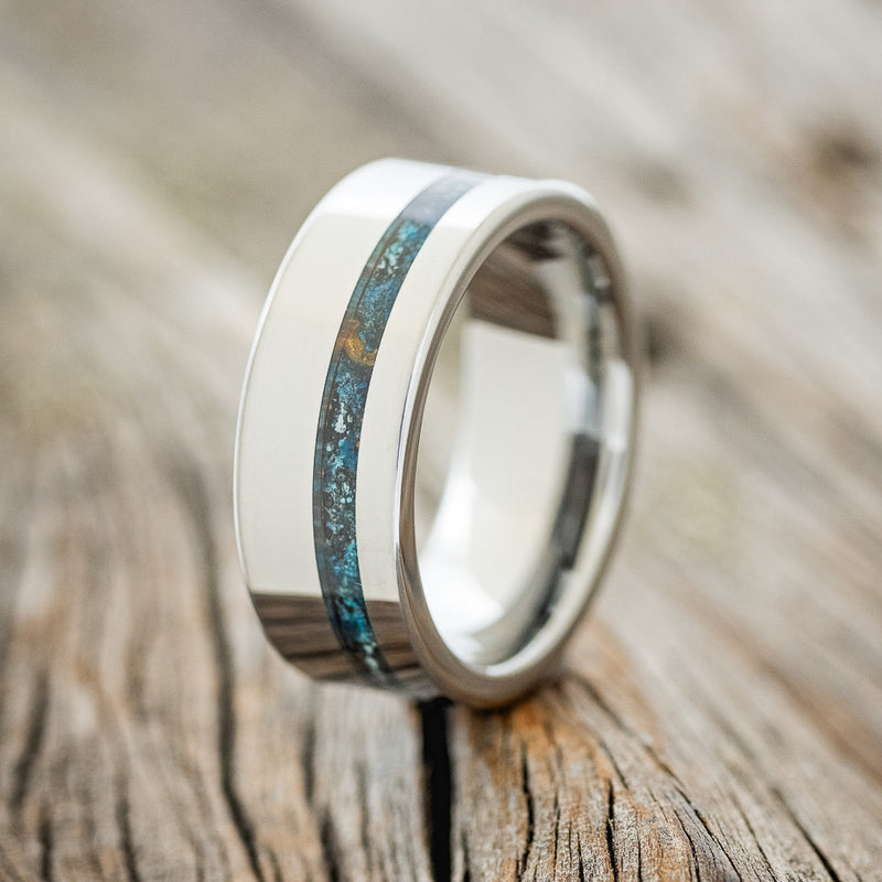 Shown here is "Vertigo", a custom, handcrafted men's wedding ring featuring a patina copper inlay, upright facing left. Additional inlay options are available upon request.
