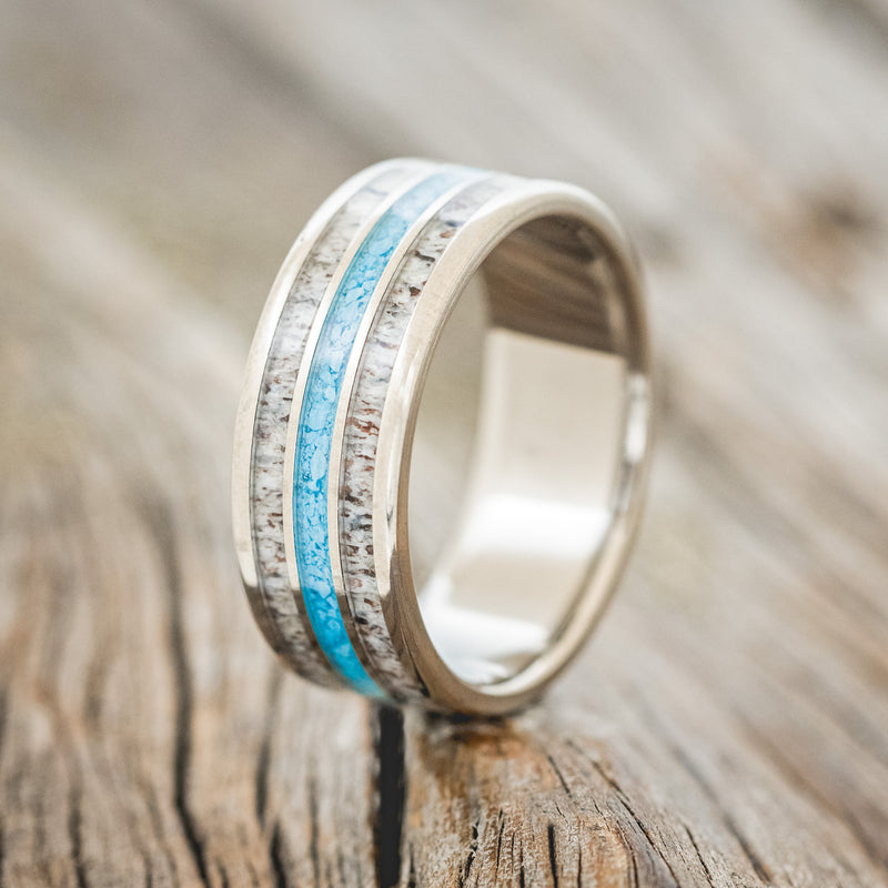 Shown here is "Rio", a custom, handcrafted men's wedding ring featuring 3 channels with antler and turquoise inlays, upright facing left.