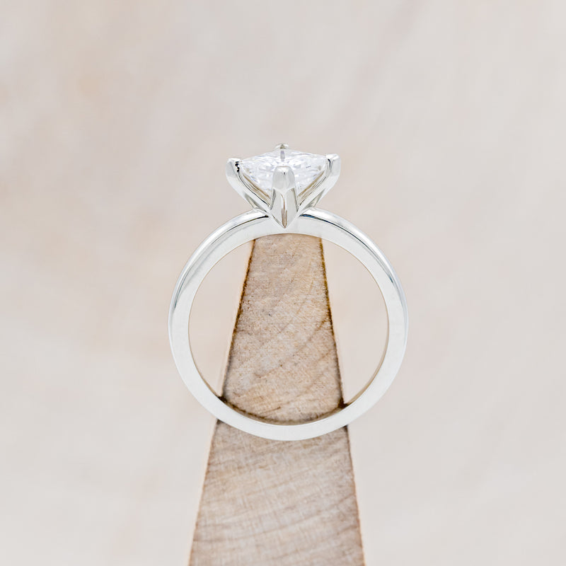 Shown here is a solitaire-style moissanite women's engagement ring, side view on stand. Many other center stone option are available upon request.