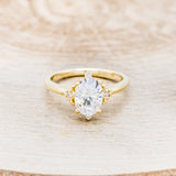 Shown here is "Zella", an oval moissanite women's engagement ring with diamond accents, front facing. Many other center stone options are available upon request.