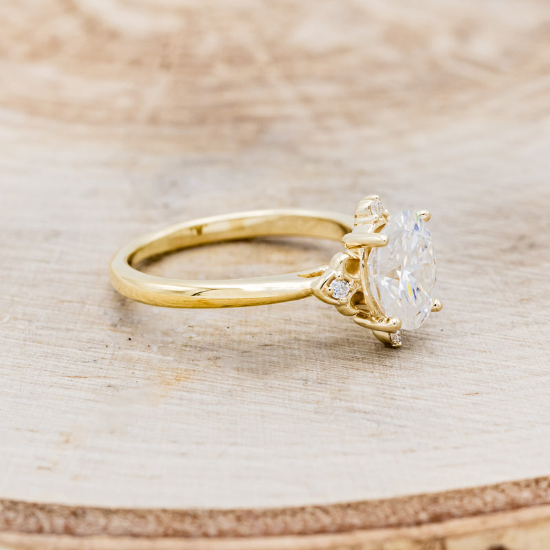 Shown here is "Zella", an oval moissanite women's engagement ring with diamond accents, facing right. Many other center stone options are available upon request.