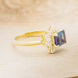 Shown here is "Aurae", an Art Deco-style lab-created alexandrite women's engagement ring with diamond accents, facing right. Many other center stone options are available upon request.