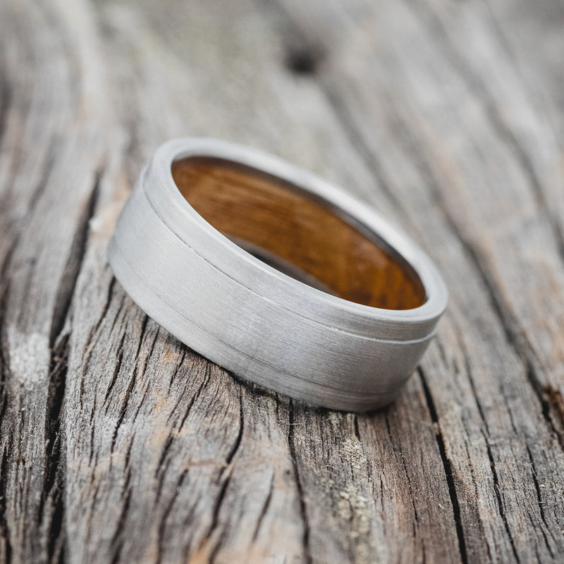 Shown here is "Sedona", a handcrafted whiskey barrel-lined men's wedding ring, featuring a brushed finish, tilted left. Additional inlay options are available upon request.