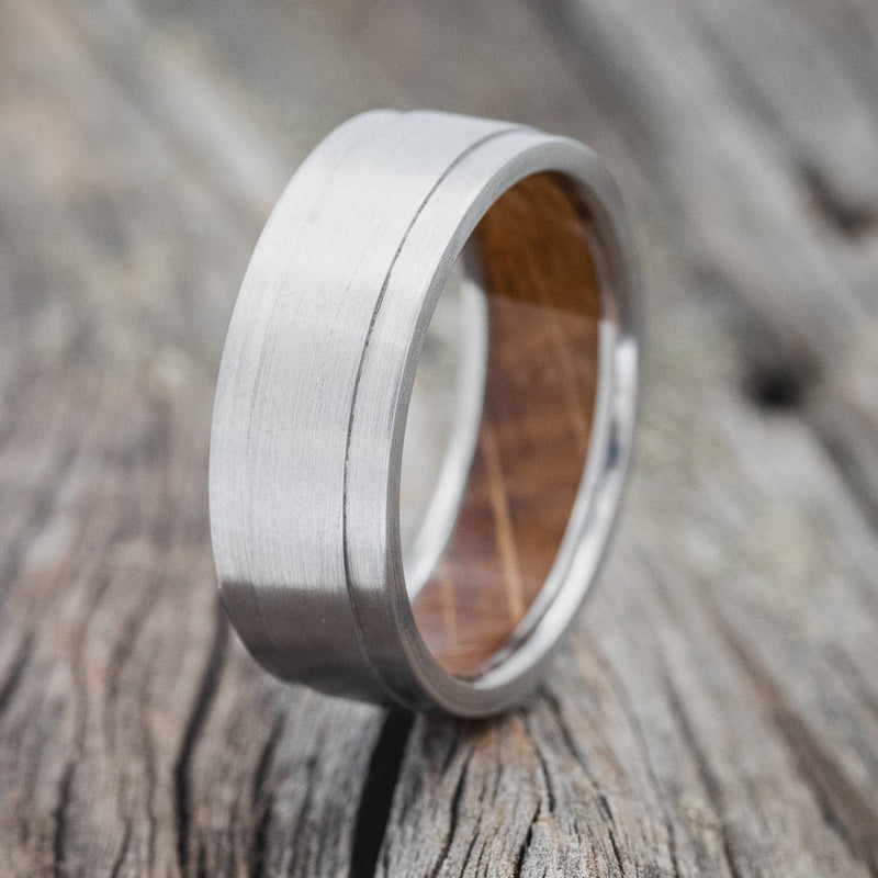 Shown here is "Sedona", a handcrafted whiskey barrel-lined men's wedding ring, featuring a brushed finish, upright facing left. Additional inlay options are available upon request.