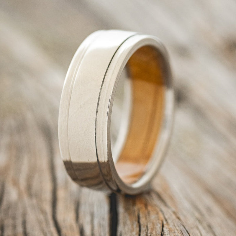 Shown here is "Sedona", a custom, handcrafted men's wedding ring featuring a raised center with a whiskey barrel oak lining, upright facing left. Additional lining options are available upon request.