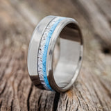 Shown here is "Castor", a custom, handcrafted men's wedding ring featuring an elk antler and hand-crushed turquoise inlay, upright facing left. Additional inlay options are available upon request.