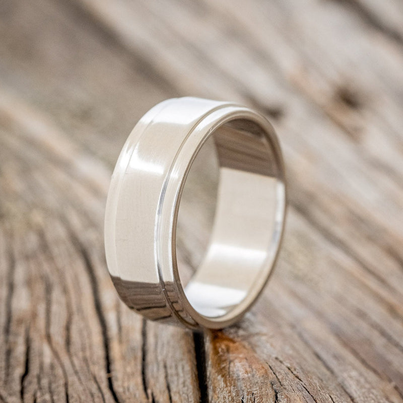 Shown here is "Sedona", a custom, handcrafted men's wedding ring featuring a solid metal band with a raised center, upright facing left. Additional inlay options are available upon request.
