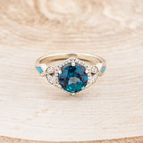 Shown here is "Lucy in the Sky", a halo-style lab-created alexandrite women's engagement ring with diamond accents and turquoise inlays, front facing. Many other center stone options are available upon request.
