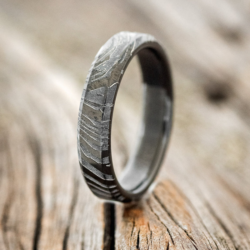 Shown here is a custom, handcrafted women's stacking band featuring a solid metal ring with a woodgrain finish, on fire-treated black zirconium band, upright facing left.