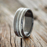 Shown here is "Cosmo", a custom, handcrafted men's wedding ring featuring diamond dust and antler inlays on a fire-treated black zirconium band, upright facing left. Additional inlay options are available upon request.
