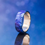 Shown here is a handcrafted men's wedding ring featuring a very unique combination of titanium and 14K rose gold, upright facing left! The titanium has been heat-treated as well as given a seascape finish. Additional inlay options are available upon request.