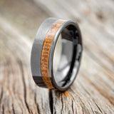 Shown here is "Castor", a custom, handcrafted men's wedding ring featuring a whiskey barrel inlay, upright facing left. Additional inlay options are available upon request.