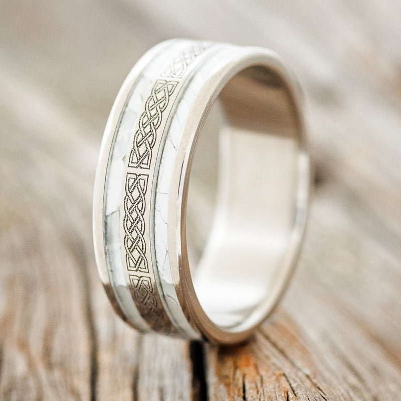 Shown here is "Ryder", a custom engraved Celtic sailor's knot-patterned men's wedding ring featuring mother of pearl inlays, upright facing left. Additional inlay options are available upon request.