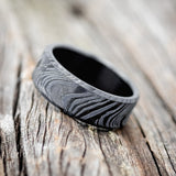 Shown here is a handcrafted men's wedding ring featuring a solid band with a woodgrain pattern, tilted left. Additional inlay options are available upon request.