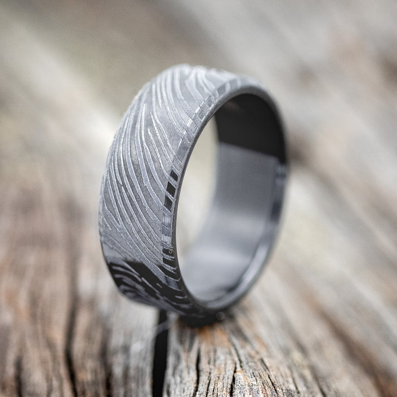 Shown here is a handcrafted men's wedding ring featuring a solid band with a woodgrain pattern, upright facing left. Additional inlay options are available upon request.