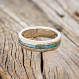 Shown here is "Nirvana", a custom, handcrafted men's wedding ring featuring a centered patina copper inlay, laying flat. Additional inlay options are available upon request.