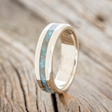 Shown here is "Nirvana", a custom, handcrafted men's wedding ring featuring a centered patina copper inlay, upright facing left. Additional inlay options are available upon request.